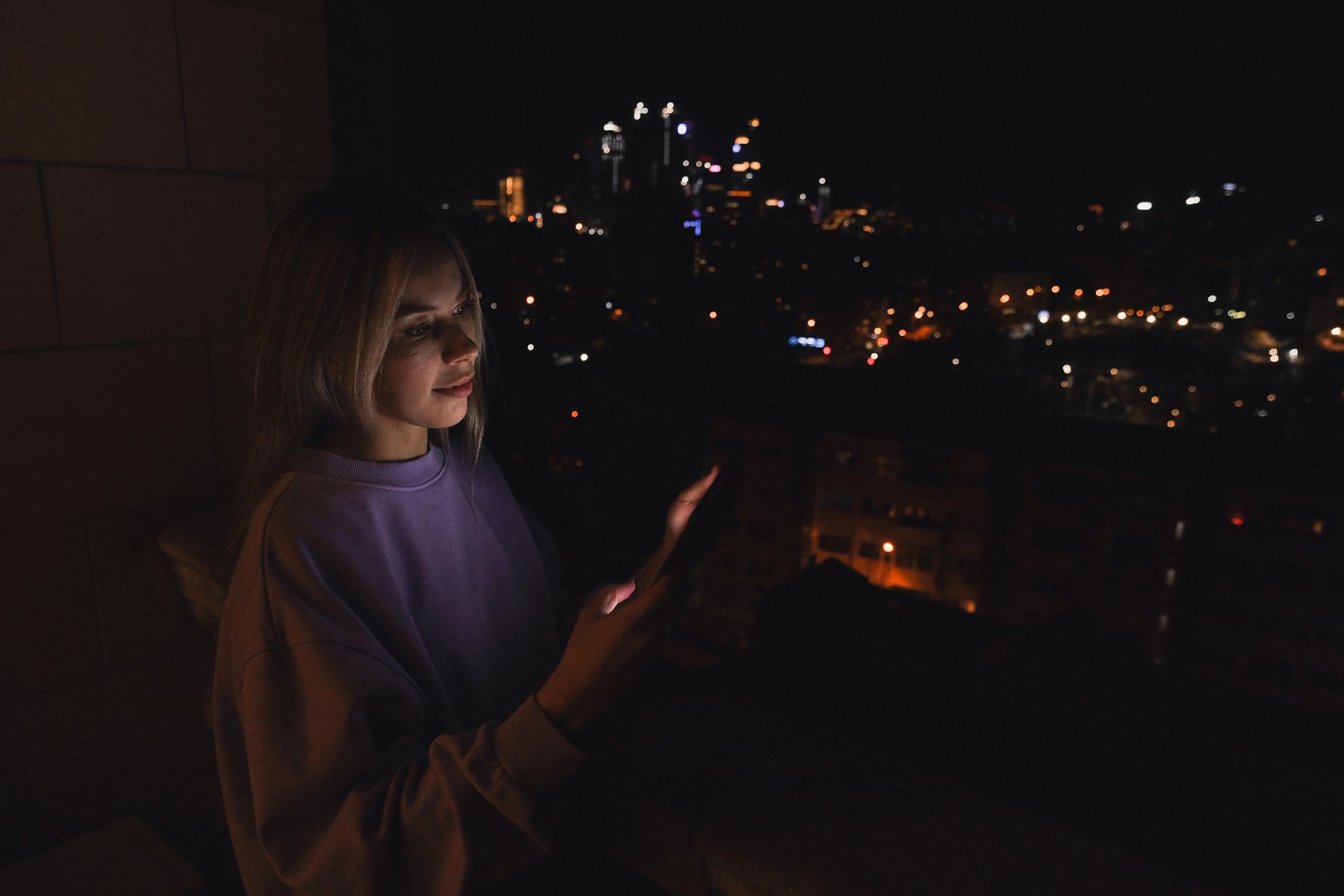 Mulher olhando o celular à noite